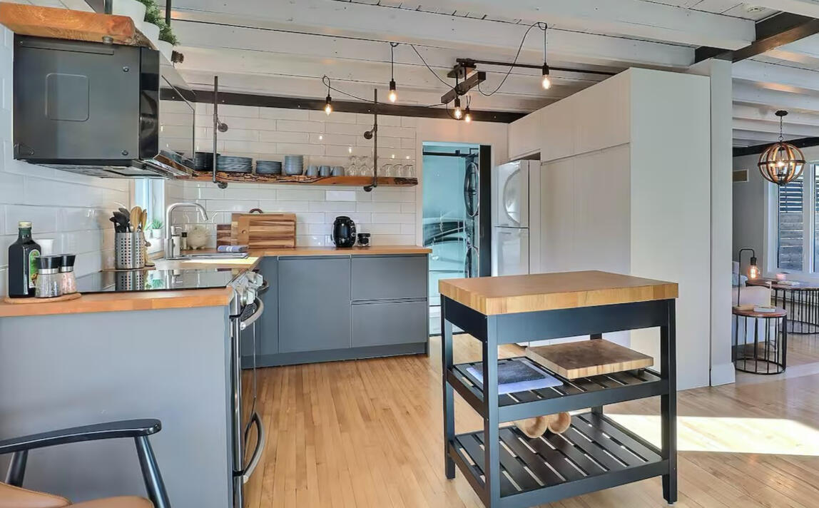Fully equipped kitchen at Chalet Le Monarque near Magog in the Eastern Townships, featuring a central island and modern design. Modern kitchen at Chalet Le Monarque near Magog, featuring a central island and hardwood floors.