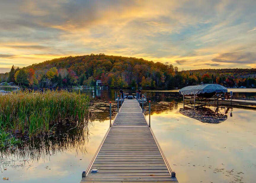 Private dock on Lake Lovering in Estrie with stunning autumn sunset views Private dock on Lake Lovering in Estrie surrounded by colorful autumn trees and calm water at sunset
