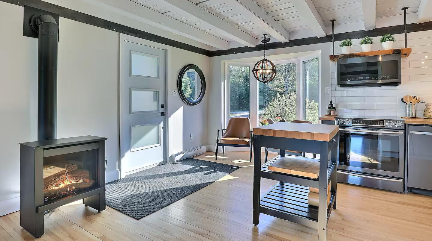 Cozy chalet kitchen with fireplace and abundant natural light Bright open concept chalet kitchen with a fireplace, large windows, and forest view bringing in natural light